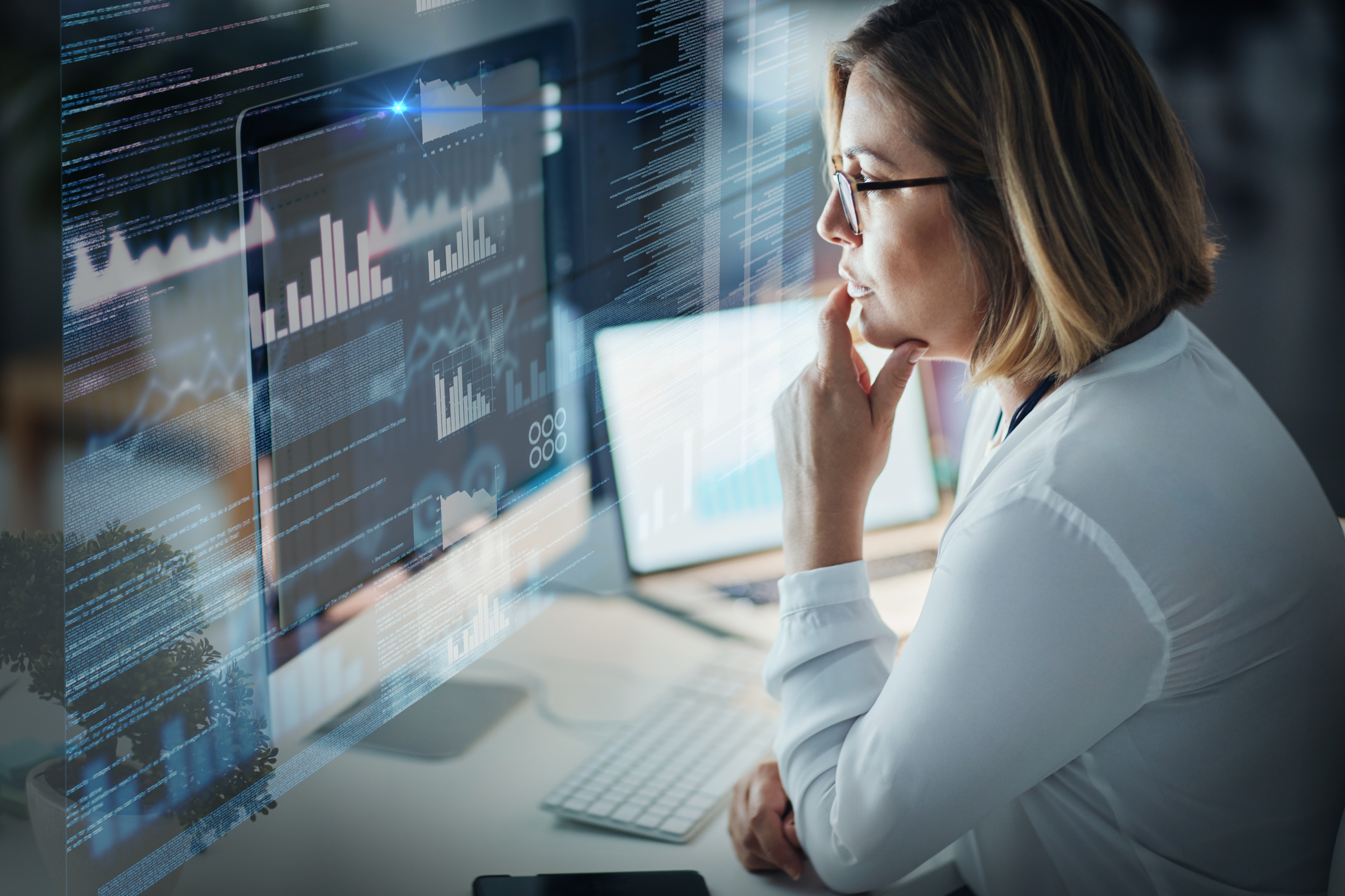 Illustrative photo of a woman analysing figures and reports on a wall of digital screens