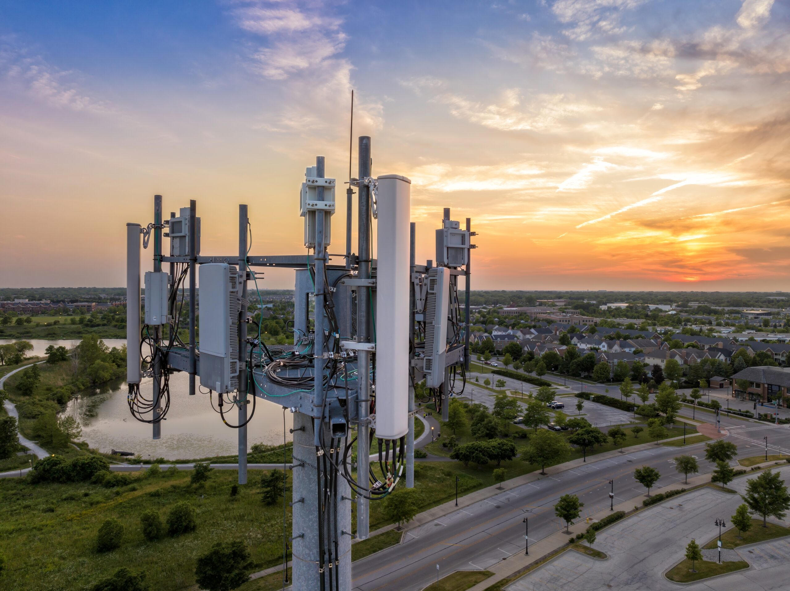 Photo of mobile phone masts at the top of a tower, with a housing estate in the background