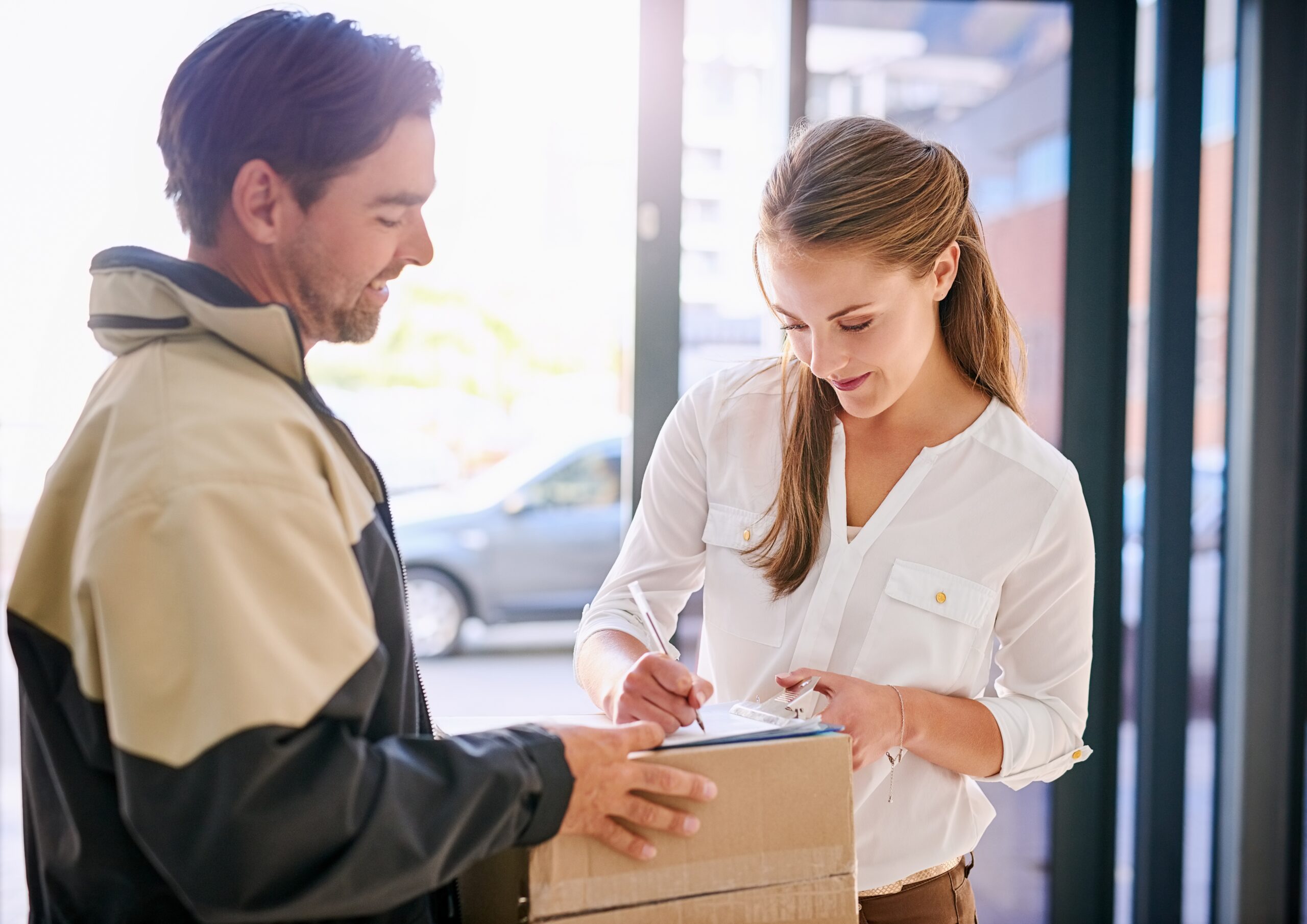 Photo of a woman signing for her parcel in the presence of the delivery driver