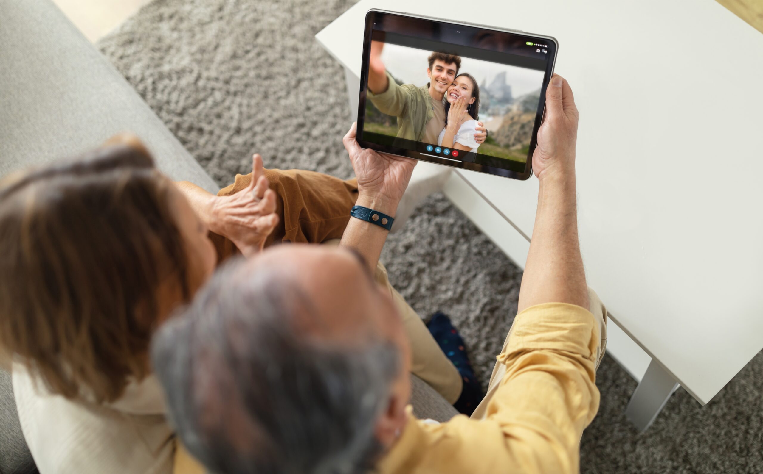 Photo of grandparents chatting with their son and daughter-in-law via video call on a tablet 